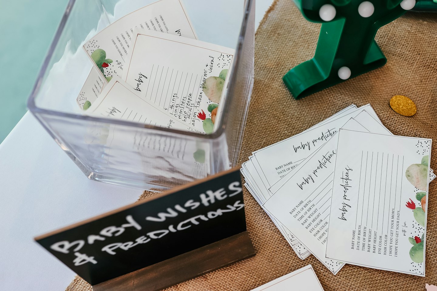 Baby shower game cards arranged on a burlap table runner.
