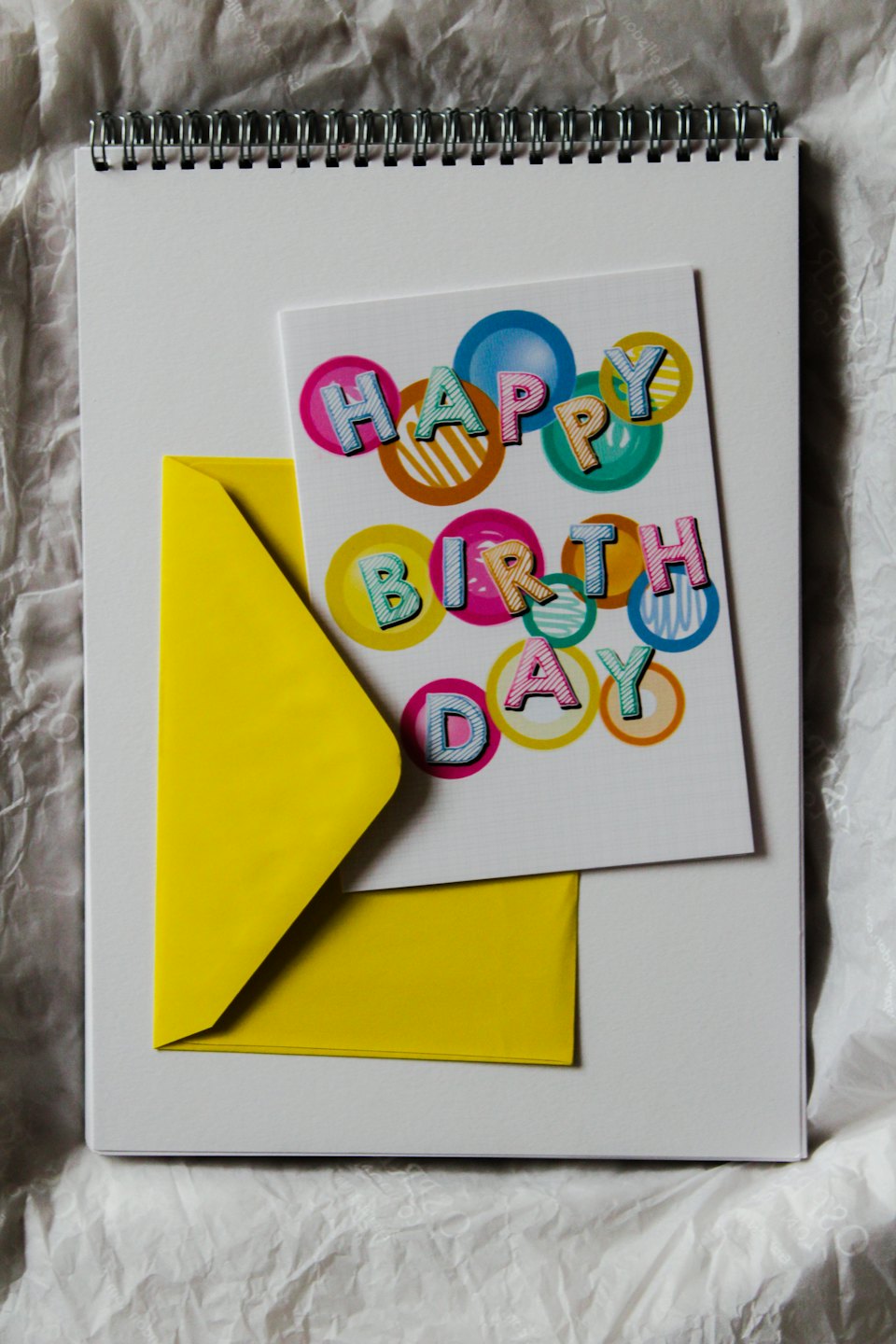 Happy Birthday card and yellow envelope on a notebook.
