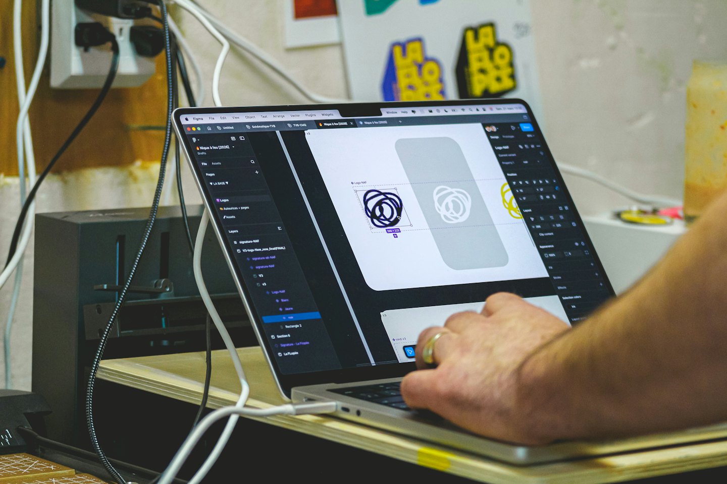 Hands editing a logo design on a laptop screen.