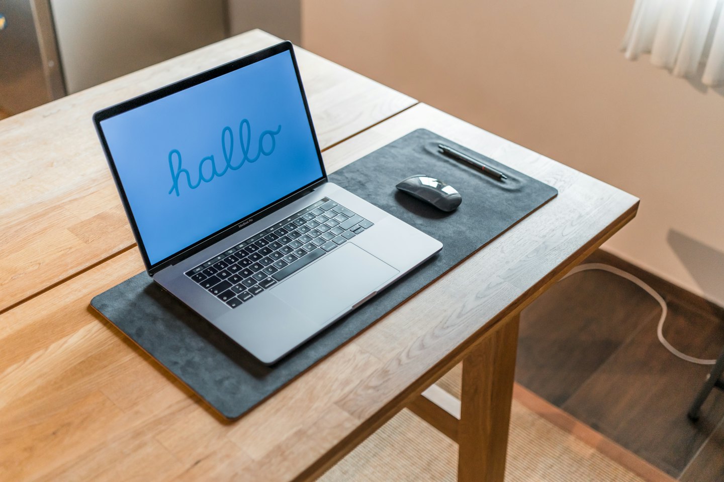 Silver laptop with blue screen and mouse on desk.